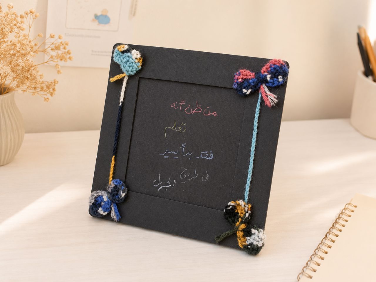 Black handmade frame with small crochet ornaments, photographed in daylight