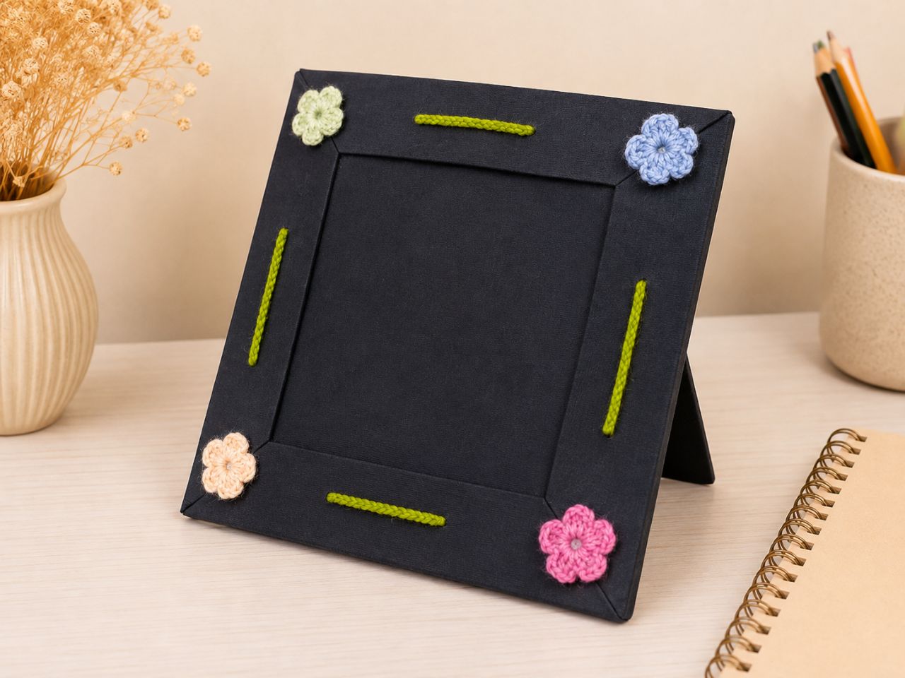 Black frame with four small crochet flowers in pastel colours