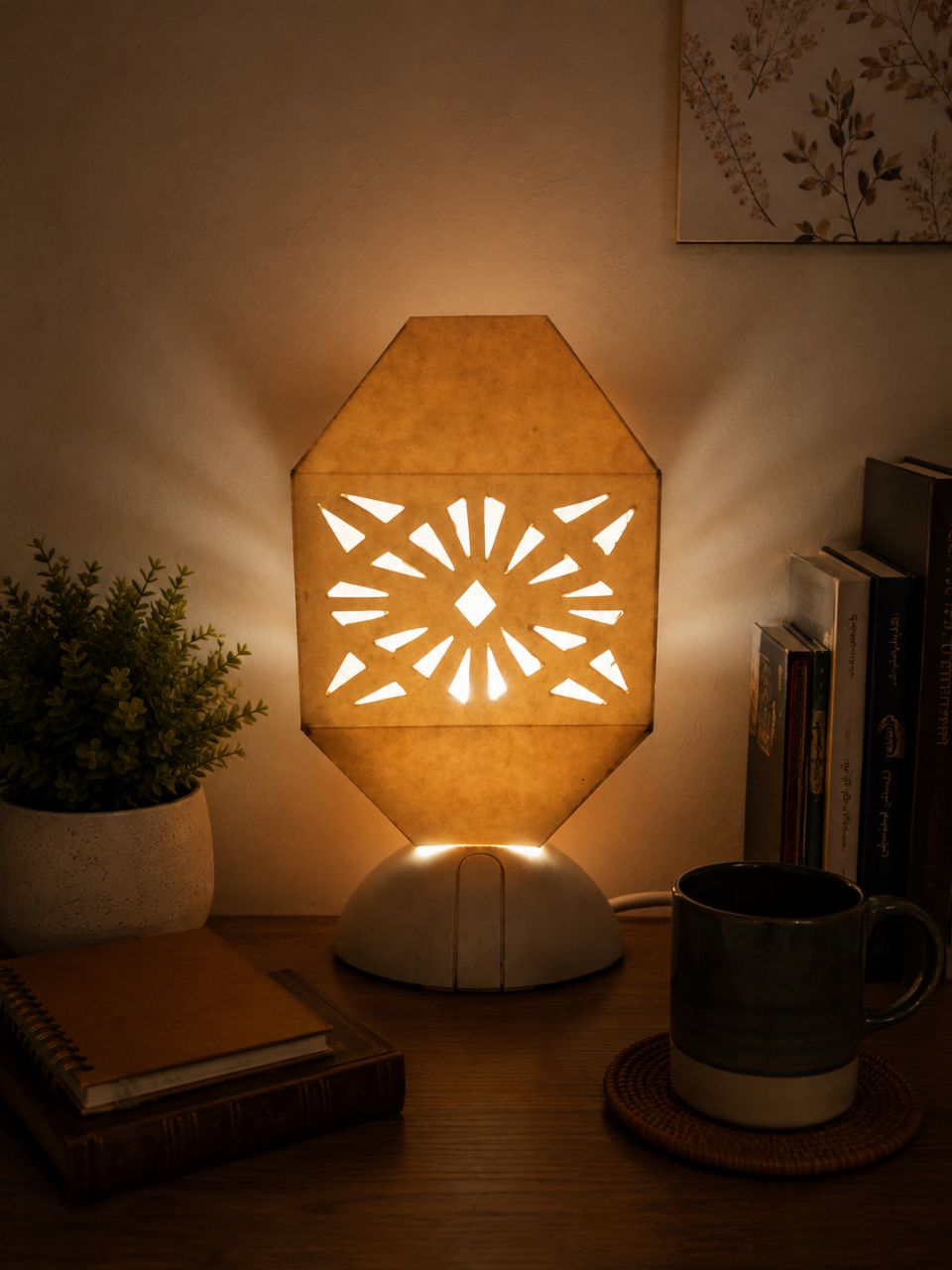 Glowing handmade paper lamp with a cut star pattern on a wooden table at night