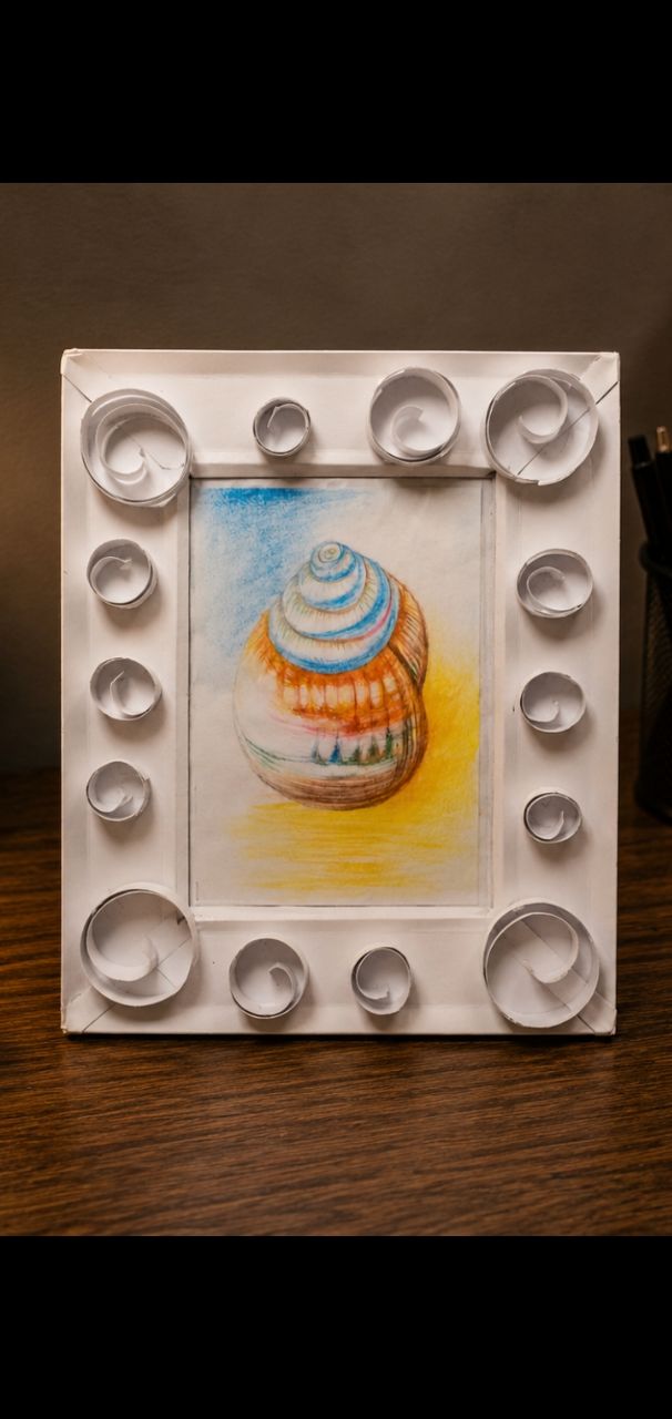 White quilled paper frame holding a coloured pencil drawing of a shell