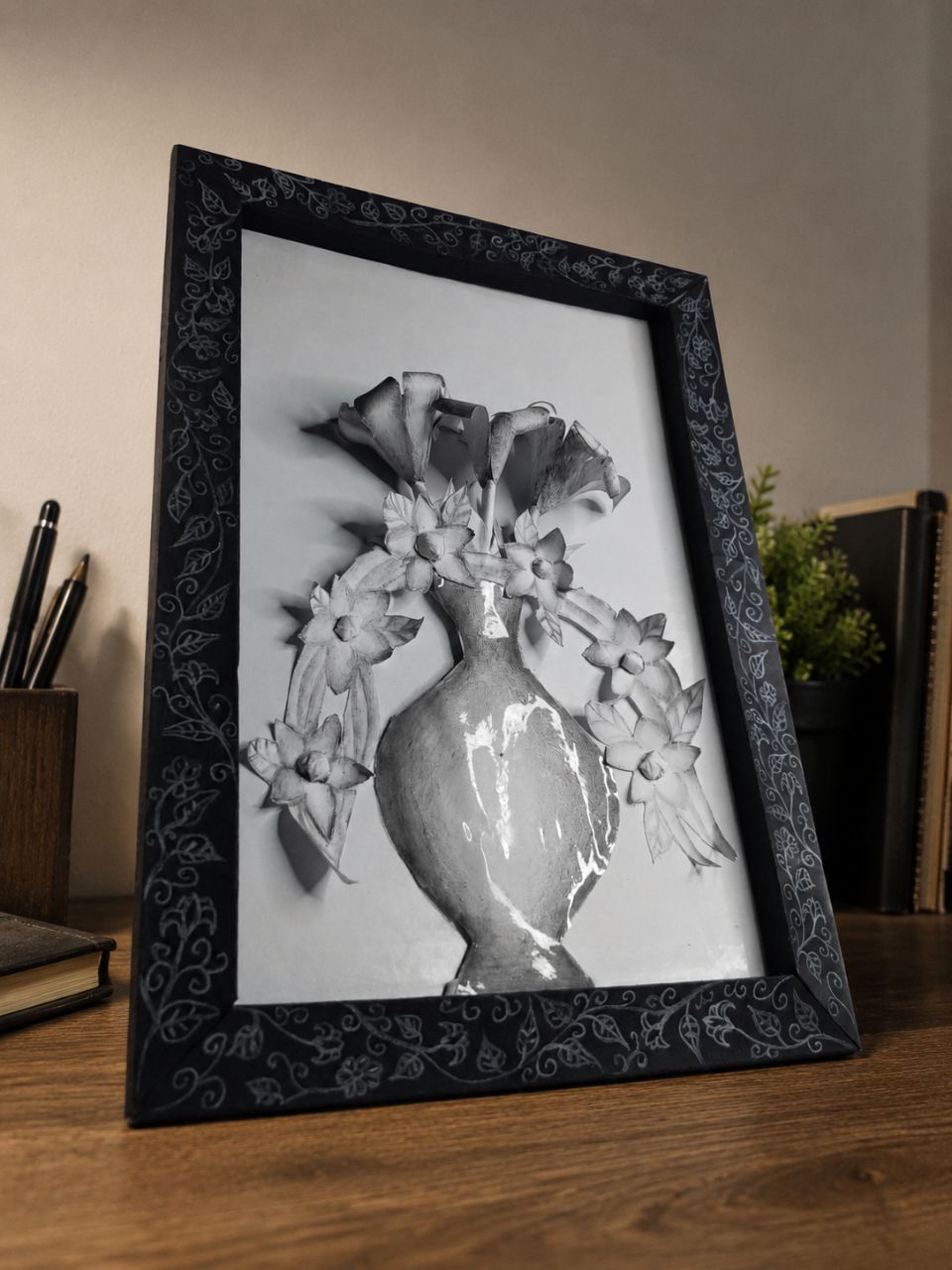 Black ornate frame with a monochrome paper vase and white paper flowers